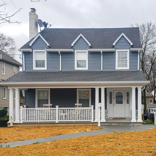 Home renovation with colonial-style porch and blue vinyl siding